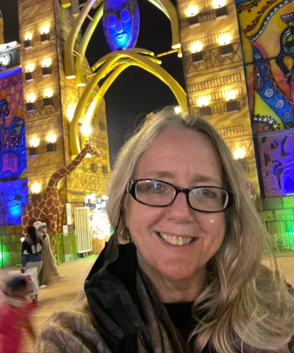Portrait of the Dawn smiling, standing under a brightly lit decorative archway. She provides Counselling in Worthing, Littlehampton & Online